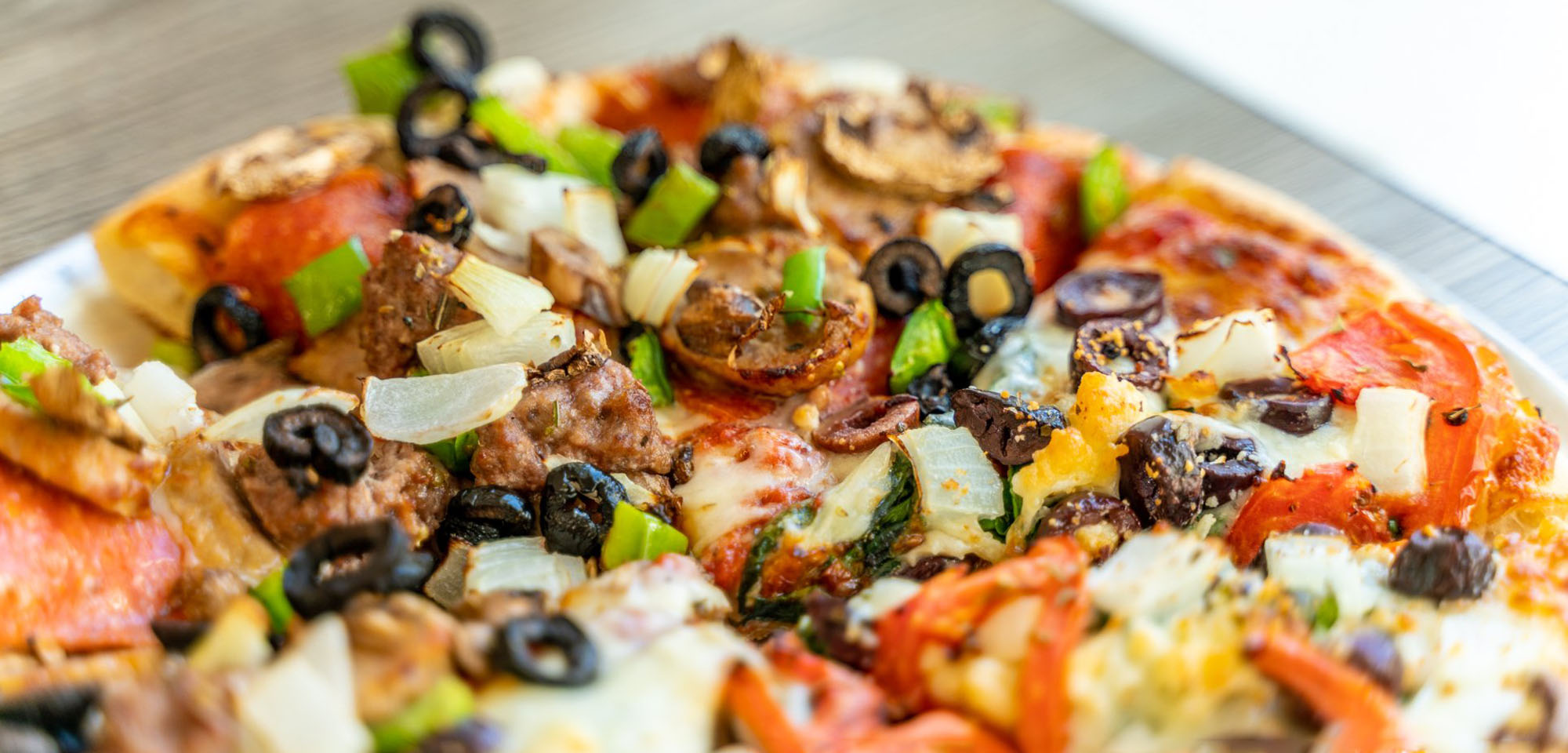 Freshly baked pizza topped with vegetables, olives and sausage