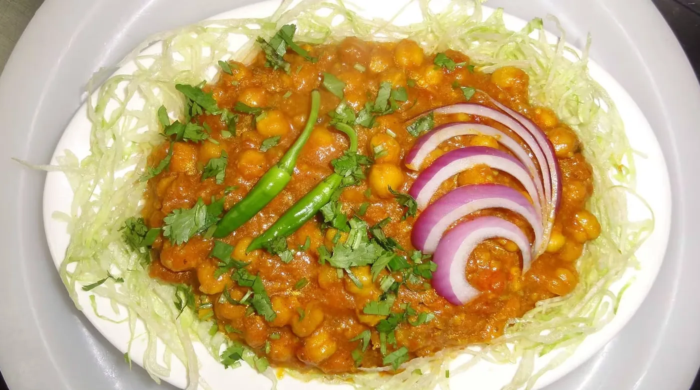 Chickpea curry garnished with cilantro and red onion